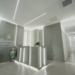 Modern and stylish reception area at Rejuve MediClinic, featuring minimalist design, ambient lighting, and the clinic's logo on the wall.